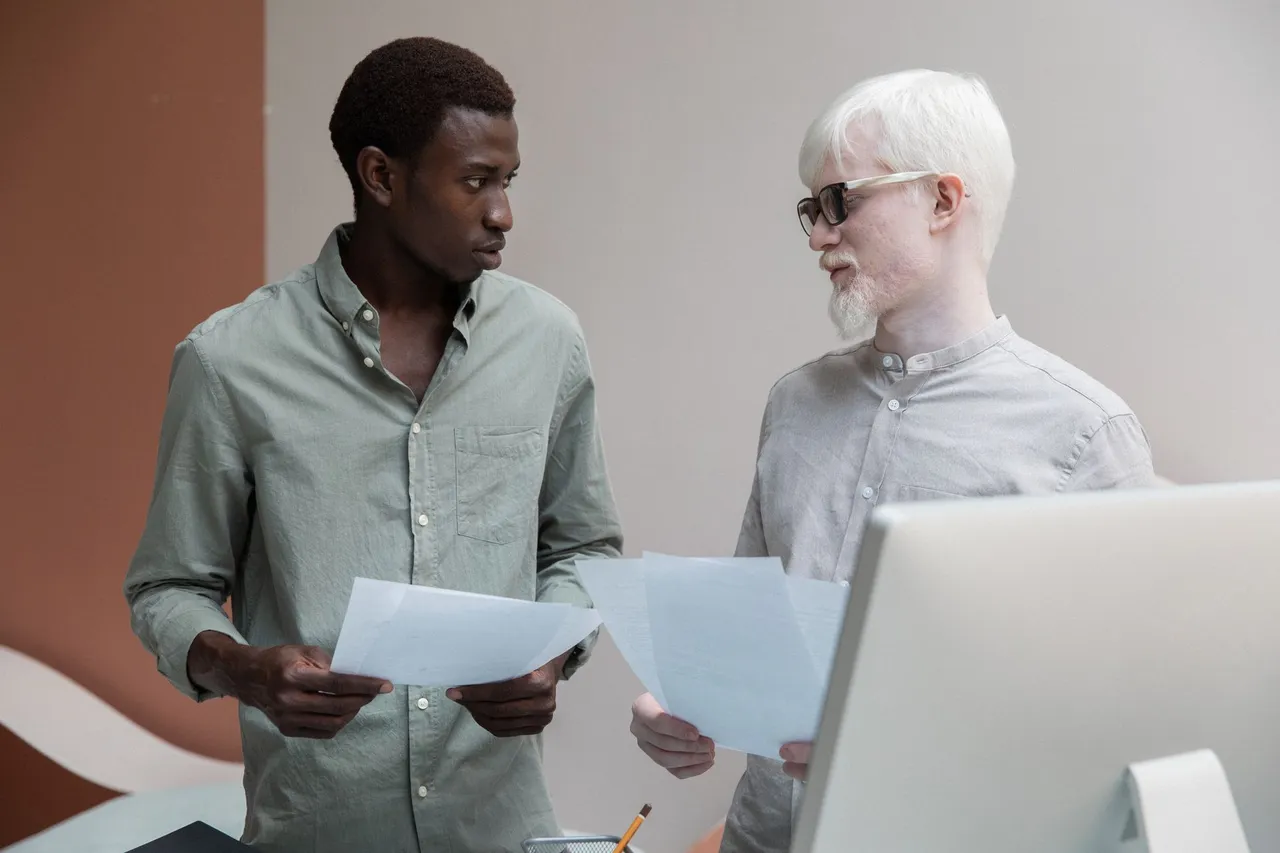 Positive men in different ages discussing project while working in loft styled workplace and looking at each other