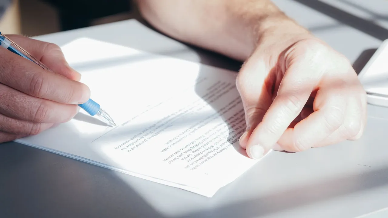 A person signing a contract with a blue pen.