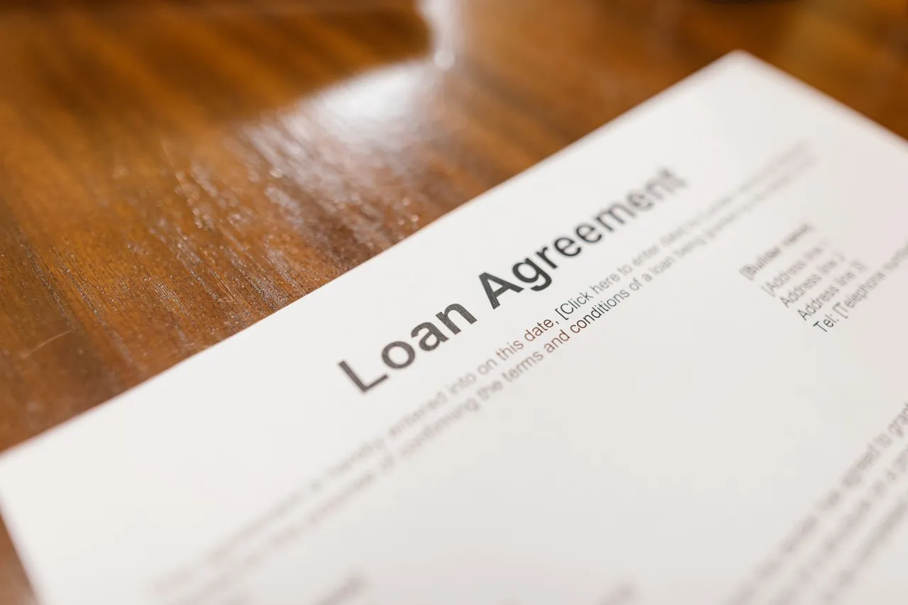 Close-up of a loan agreement document on a wooden table.