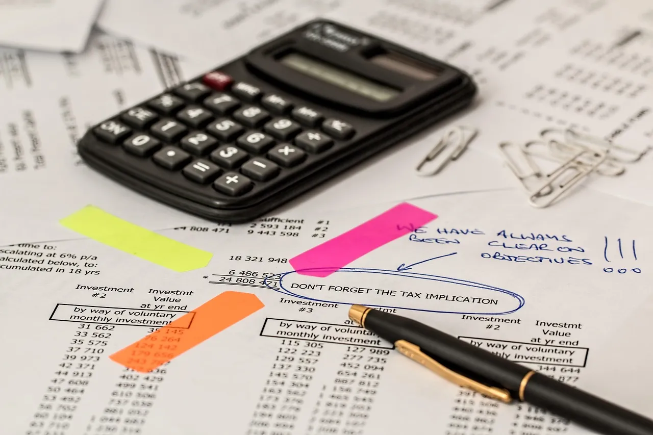 A calculator on a desk next to financial papers.