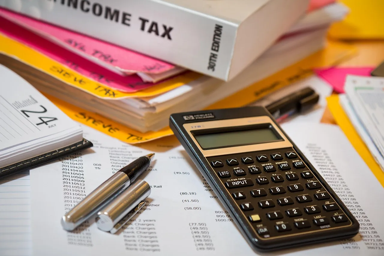 A calculator and tax documents on a desk.